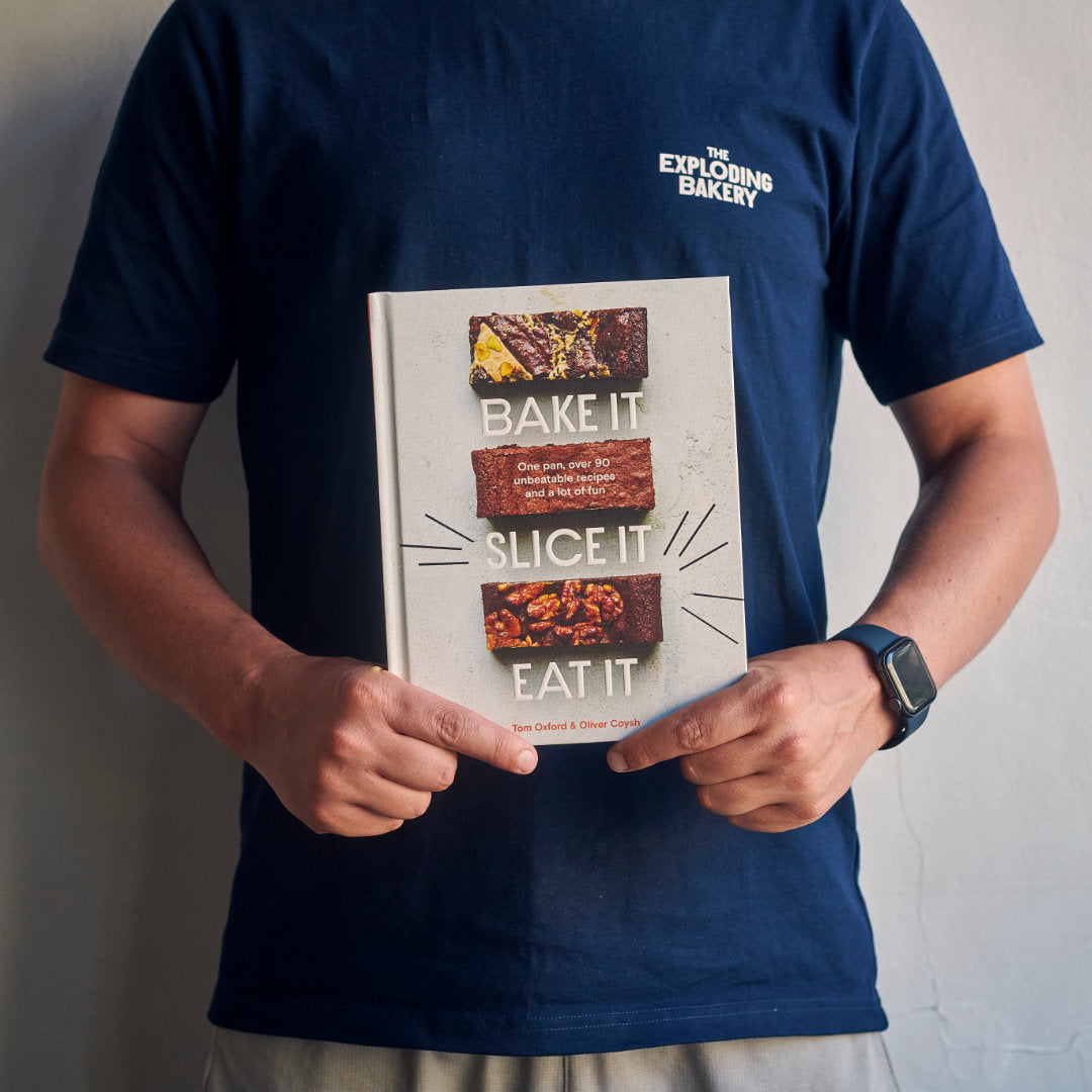 Someone holding the Exploding Bakery book, BAKE IT, SLICE IT, EAT IT.